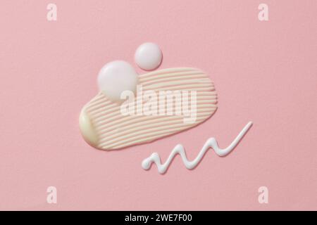 Taches blanches cosmétiques et gouttes de crème ou de lotion sur le fond rose. Texture des produits cosmétiques de soin de la peau Banque D'Images