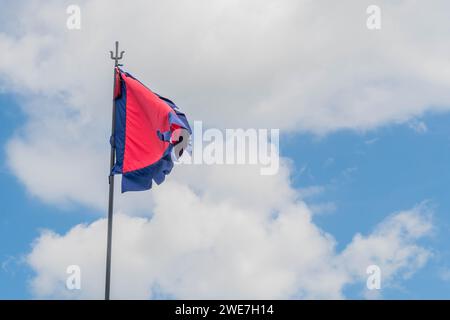 Drapeau rouge avec frange bleue sur poteau métallique sous ciel bleu nuageux en Corée du Sud Banque D'Images