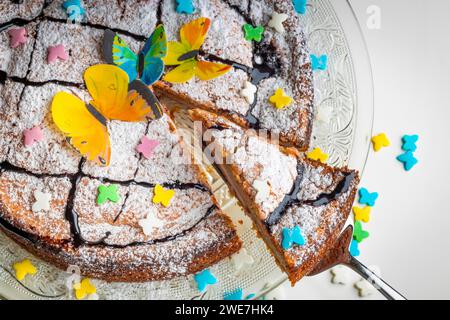 Gâteau succulent avec décoration papillon et saupoudrages colorés sur une assiette en verre, base blanche Banque D'Images