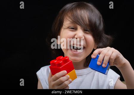 Les mains des enfants jouer avec des blocs colorés les blocs de lego Banque D'Images