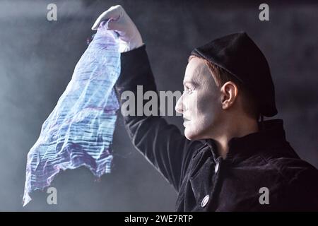 Portrait spectaculaire d'un artiste mime jouant sur scène et tenant un tissu chatoyant à la lumière, l'espace de copie Banque D'Images