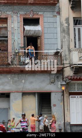 Une femme debout sur le balcon d'un immeuble utilise une corde pour soulever son sac acheté chez un vendeur de rue dans la vieille Havane, à Cuba. Banque D'Images