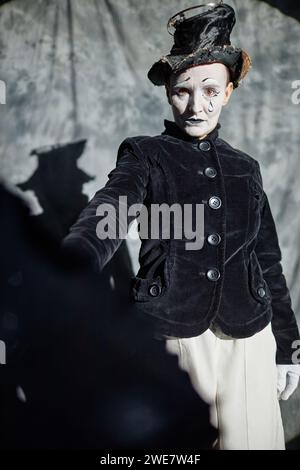 Portrait dramatique d'artiste mime féminin jouant sur scène sous les projecteurs et tenant un parapluie Banque D'Images