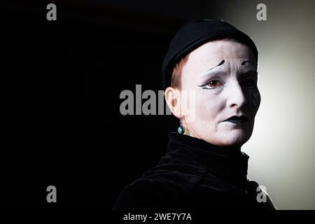 Portrait minimal de triste mime debout dans l'éclairage de contour et regardant la caméra sur fond noir, espace de copie Banque D'Images