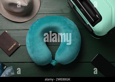 Composition Flat Lay avec oreiller de voyage turquoise et smartphone sur fond en bois vert Banque D'Images