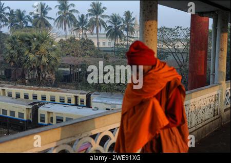 24.01.2014, Yangon, Myanmar, Asie - Un homme portant un châle traverse le pont supérieur de Pansodan à l'aube avec la gare centrale de Yangon derrière. Banque D'Images