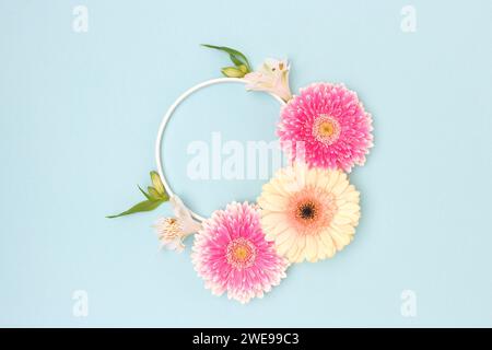 Couronne faite de feuilles vertes, alstroemeria et fleurs de gerbera sur un fond bleu. Banque D'Images