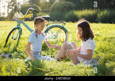 Deux filles profitent de l'été et des vacances ensemble passant du temps sur la pelouse verte dans le parc, Banque D'Images