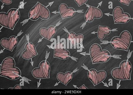 Motif avec des coeurs et des flèches de Cupidon dessinés sur un tableau noir. Fond de Saint Valentin Banque D'Images