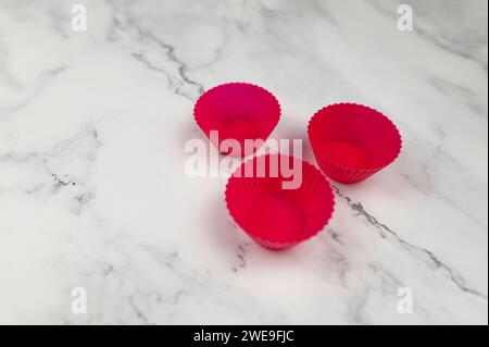 Vue de dessus des étuis cupcakes en silicone sur fond de marbre blanc. Cuisson des muffins et cupcakes, pose à plat, espace de copie. Banque D'Images