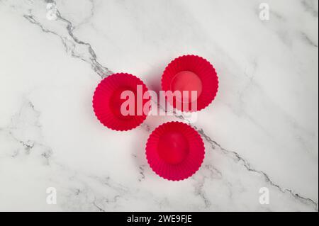 Vue de dessus des étuis cupcakes en silicone sur fond de marbre blanc. Cuisson des muffins et cupcakes, pose à plat, espace de copie. Banque D'Images