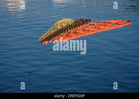 Barrières de marquage enroulées et pliées flottant sur la baie océanique Banque D'Images