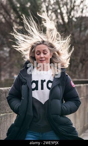 Une femme venteuse à Leeds. La tempête Jocelyn a provoqué de nouvelles perturbations dans la majeure partie du Royaume-Uni, moins de deux jours après que la tempête Isha ait fait deux morts et des milliers de sans électricité. Date de la photo : mercredi 24 janvier 2024. Banque D'Images