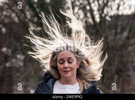Une femme venteuse à Leeds. La tempête Jocelyn a provoqué de nouvelles perturbations dans la majeure partie du Royaume-Uni, moins de deux jours après que la tempête Isha ait fait deux morts et des milliers de sans électricité. Date de la photo : mercredi 24 janvier 2024. Banque D'Images