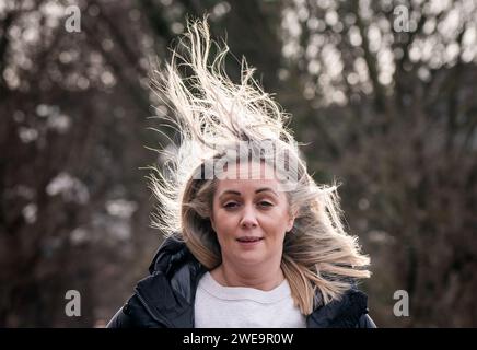 Une femme venteuse à Leeds. La tempête Jocelyn a provoqué de nouvelles perturbations dans la majeure partie du Royaume-Uni, moins de deux jours après que la tempête Isha ait fait deux morts et des milliers de sans électricité. Date de la photo : mercredi 24 janvier 2024. Banque D'Images