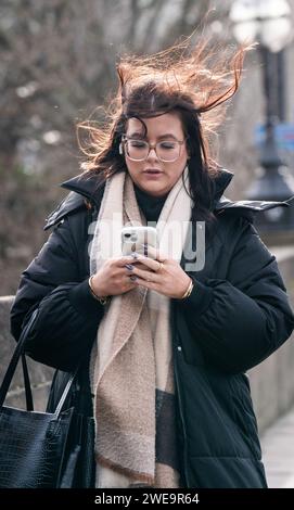 Une femme venteuse à Leeds. La tempête Jocelyn a provoqué de nouvelles perturbations dans la majeure partie du Royaume-Uni, moins de deux jours après que la tempête Isha ait fait deux morts et des milliers de sans électricité. Date de la photo : mercredi 24 janvier 2024. Banque D'Images