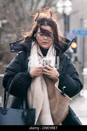 Une femme venteuse à Leeds. La tempête Jocelyn a provoqué de nouvelles perturbations dans la majeure partie du Royaume-Uni, moins de deux jours après que la tempête Isha ait fait deux morts et des milliers de sans électricité. Date de la photo : mercredi 24 janvier 2024. Banque D'Images