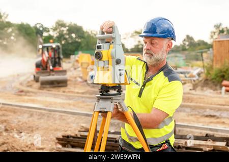 Un géomètre ingénieur de chantier travaillant avec l'équipement EDM de la station totale théodolite sur un chantier de construction de bâtiments à l'extérieur Banque D'Images