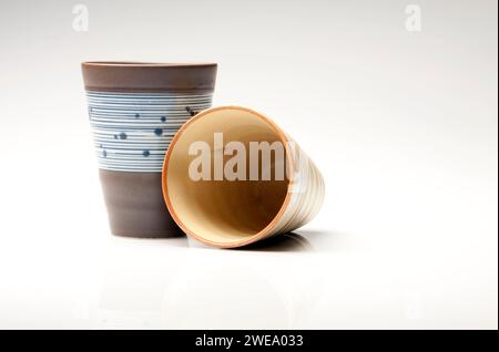 Deux tasses à café / thé en argile peintes sur un fond de studio blanc. Banque D'Images