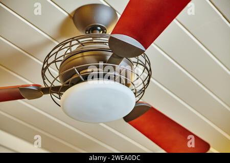 Ventilateur de plafond rouge et acajou moderne avec lumière, vue vers le haut Banque D'Images