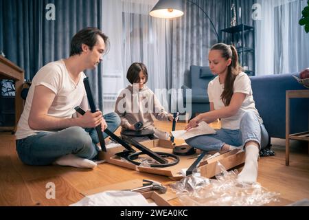 La famille travaille ensemble sur l'auto-assemblage de meubles à partir de zéro. Banque D'Images