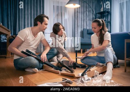 La famille fabrique avec enthousiasme une chaise achetée dans un magasin de meubles. Banque D'Images