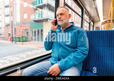 portrait d'un homme barbu dans une veste bleue parlant au téléphone dans un bus ou un trum. Concept de style de vie Banque D'Images