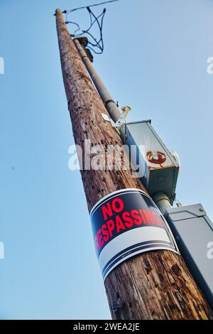 Panneau d'interdiction d'intrusion sur le poteau utilitaire patiné, perspective du ciel dégagé Banque D'Images