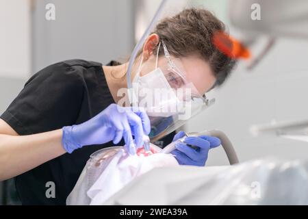 Une dentiste traite les dents d'un patient pour la carie à l'aide d'instruments dentaires. Banque D'Images