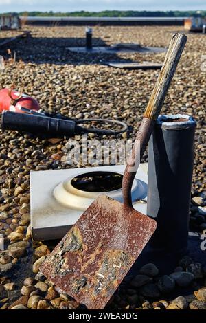 Pelle rouillée et outils de toiture industrielle sur surface gravillonnée Banque D'Images