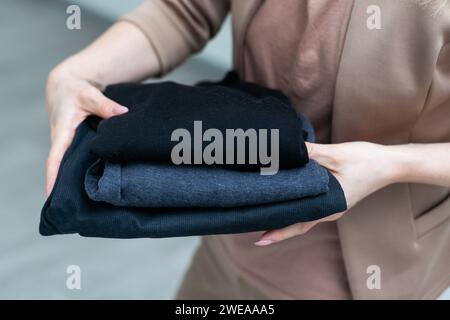 Une femme met des vêtements pour un don de vêtements dans une boîte ou des mordides Banque D'Images