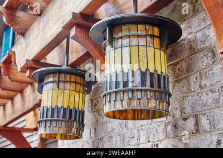 Lanternes rustiques en verre teinté sur mur de briques - décor d'éclairage extérieur Banque D'Images