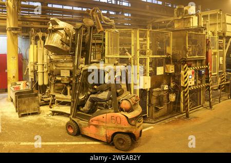 Annaberg Buchholz, Allemagne. 24 janvier 2024. Chez Handtmann Leichtmetallgießerei Annaberg GmbH, un employé remplit une machine de moulage sous pression avec de l’aluminium fondu. 328 employés produisent 60 000 tonnes de pièces moulées spéciales sur le site des Monts Ore, principalement pour l'industrie automobile. Fondée en 1926 en tant que fonderie DKW, des pièces pour motos MZ ont été fabriquées ici à l'époque de la RDA. Après la réunification, la société a été reprise par le groupe Handtmann de Biberach et a continué à s'étendre. Crédit : Jan Woitas/dpa/Alamy Live News Banque D'Images