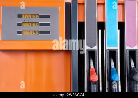 Image de fond en gros plan des buses en rangée sur la pompe à carburant orange dans la station-service moderne Banque D'Images