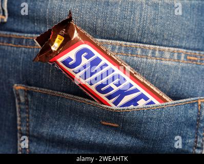 Tambov, Fédération de Russie - 23 janvier 2024 barre de chocolat Snickers dans une poche arrière de jeans Banque D'Images