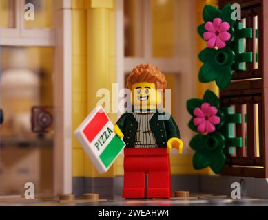 Tambov, Fédération de Russie - 21 janvier 2024 Une minifigurine Lego homme avec une boîte à pizza debout près de la maison Lego Banque D'Images