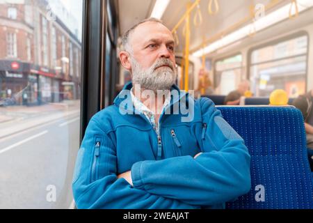 portrait d'un homme barbu dans une veste bleue parlant au téléphone dans un bus ou un trum. Concept de style de vie Banque D'Images