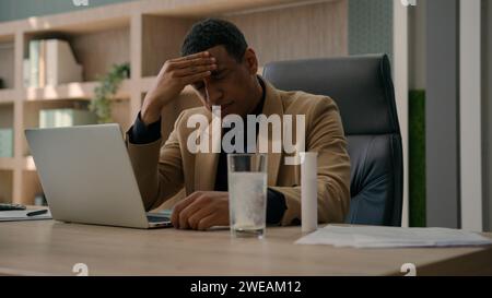 Afro-américain surmené homme d'affaires jeter la pilule pétillante dans le verre de l'eau appliquer le supplément de médicament dissolvant le comprimé analgésique avec des bulles souffrent Banque D'Images