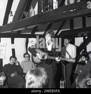 1970, historique, des gens à l'intérieur d'un pub à cadre en bois, le Red Lion à Stevenage Old Town, pour une session de jam de musique folklorique, Angleterre, Royaume-Uni. Une affiche sur le mur dit, une soirée folklorique au Stevenage College of Further Education, 14 février 1970. Banque D'Images