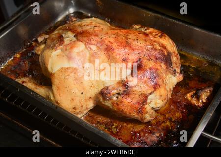 Gros plan d'un poulet entier rôti dans une plaque de four maison, donnant une peau croustillante et dorée prête à l'emploi Banque D'Images