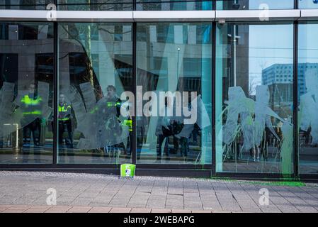 Amsterdam, Hollande du Nord, pays-Bas. 24 janvier 2024. La police néerlandaise se tient derrière les fenêtres avant de One Dyas, ses fenêtres peintes en vert par des militants pour le climat. Le 24 janvier 2024, des militants pour le climat ont protesté contre les forages en haute mer effectués par un certain Dyas au siège de la société à Amsterdam. Demain, le 25 janvier, un Dyas sera en cour au sujet de sa demande de permis d'exploration et de forage en mer du Nord. (Image de crédit : © James Petermeier/ZUMA Press Wire) USAGE ÉDITORIAL SEULEMENT! Non destiné à UN USAGE commercial ! Banque D'Images