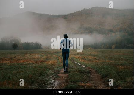 Jeune Trail Runner en automne nature : embrasser la tranquillité au milieu des sentiers embrassés de brouillard Banque D'Images