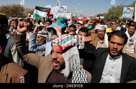 Sanaa, Sanaa, Yémen. 24 janvier 2024. Des manifestants brandissent des drapeaux palestiniens et yéménites, des pancartes représentant et les emblèmes du groupe Houthi lors d'une manifestation contre les frappes aériennes soutenues menées par les États-Unis sur le Yémen, et en solidarité avec le peuple palestinien dans un conflit en cours entre Israël et le Hamas à Gaza.le porte-parole militaire houthi Yahya Saree a rapporté une confrontation entre leurs forces et plusieurs destroyers et navires de guerre américains dans le golfe d'Aden et Bab al-Mandab aujourd'hui. Les navires américains gardaient deux navires commerciaux, et pendant l'affrontement, l'un des navires américains était stru Banque D'Images