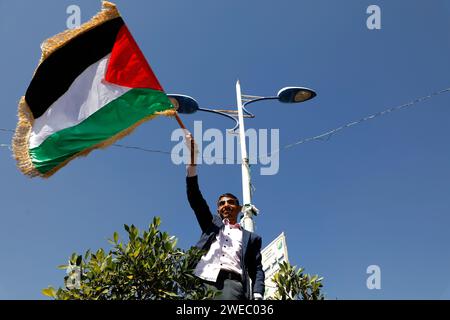 Sanaa, Sanaa, Yémen. 24 janvier 2024. Un manifestant brandit le drapeau palestinien, lors d'une manifestation contre les frappes aériennes soutenues menées par les États-Unis sur le Yémen, et en solidarité avec le peuple palestinien dans un conflit en cours entre Israël et le Hamas à Gaza.le porte-parole militaire houthi Yahya Saree a rapporté une confrontation entre leurs forces et plusieurs destroyers et navires de guerre américains dans le golfe d'Aden et Bab al-Mandab aujourd'hui. Les navires américains gardaient deux navires commerciaux, et pendant l'affrontement, l'un des navires américains a été frappé. En conséquence, les deux navires marchands américains ont été contraints Banque D'Images