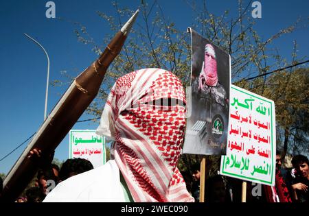 Sanaa, Sanaa, Yémen. 24 janvier 2024. Un homme porte un keffiyeh palestinien traditionnel devant un faux missile et chante des slogans anti-israéliens et des frappes aériennes soutenues dirigées par les États-Unis sur le Yémen lors d'une manifestation de solidarité avec le peuple palestinien dans un conflit en cours entre Israël et le Hamas à Gaza. Le porte-parole militaire houthi Yahya Saree a rapporté une confrontation entre leurs forces et plusieurs destroyers et navires de guerre américains dans le golfe d'Aden et Bab al-Mandab aujourd'hui. Les navires américains gardaient deux navires commerciaux, et pendant l'affrontement, l'un des navires américains a été frappé. AS Banque D'Images