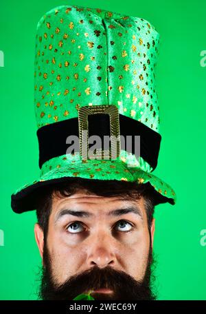 Fête de la Saint Patrick. Homme pensif en haut-de-forme vert à la fête de Patrick. Gros plan portrait gars barbu sérieux dans le chapeau de leprechaun vert avec Banque D'Images