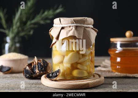 Ail au miel dans un pot en verre et ail noir fermenté sur une table en bois Banque D'Images