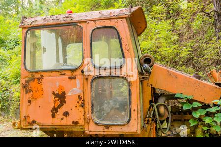 Partie gauche de la cabine d'un vieux bulldozer rouillé en panne abandonné en pleine nature Banque D'Images