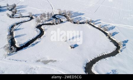 Drone shot de la rivière Schmutter serpentant naturellement à travers le paysage hivernal enneigé du parc naturel Western Forests près d'Augsbourg Banque D'Images