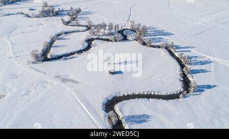 Drone shot de la rivière Schmutter serpentant naturellement à travers le paysage hivernal enneigé du parc naturel Western Forests près d'Augsbourg Banque D'Images